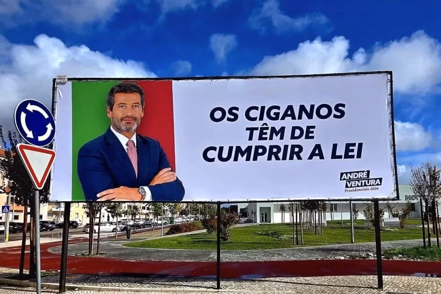 Cartaz de campanha com fotografia de André Ventura, candidato presidencial, ao lado da frase 'Os ciganos têm de cumprir a lei', destacando a polémica referida no artigo.