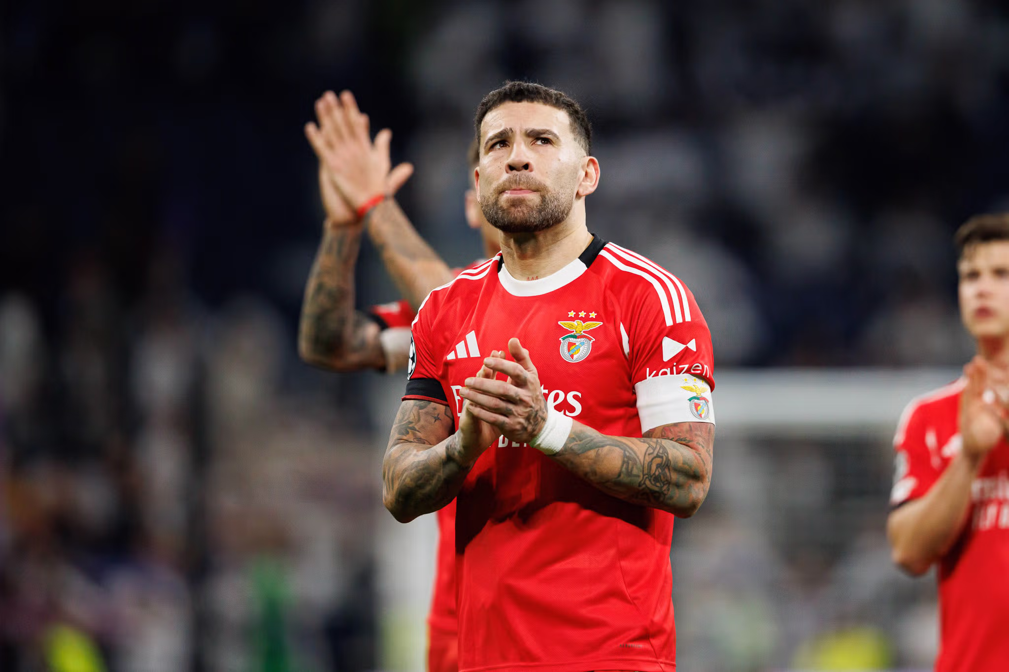 Jogador do Benfica a aplaudir em campo, com o equipamento vermelho do clube, durante um jogo de futebol.